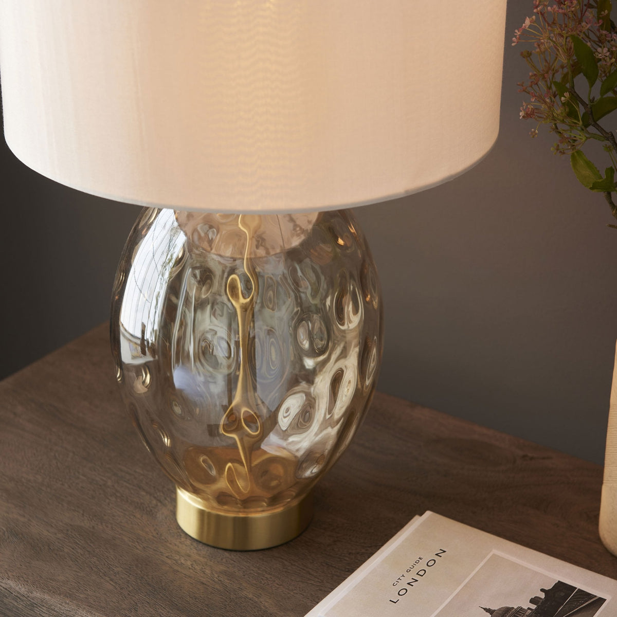 A close up of the Dimpled Glass Table Lamp on a dark wooden table.