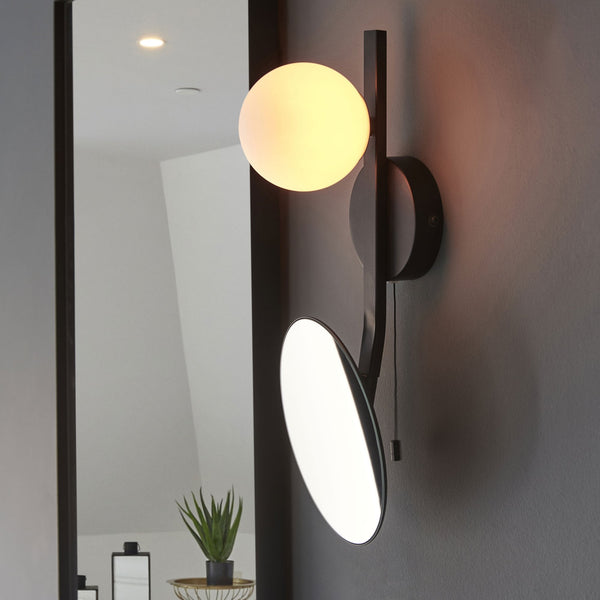 Modern black wall light featuring a spherical glass shade and an illuminated circular mirror.