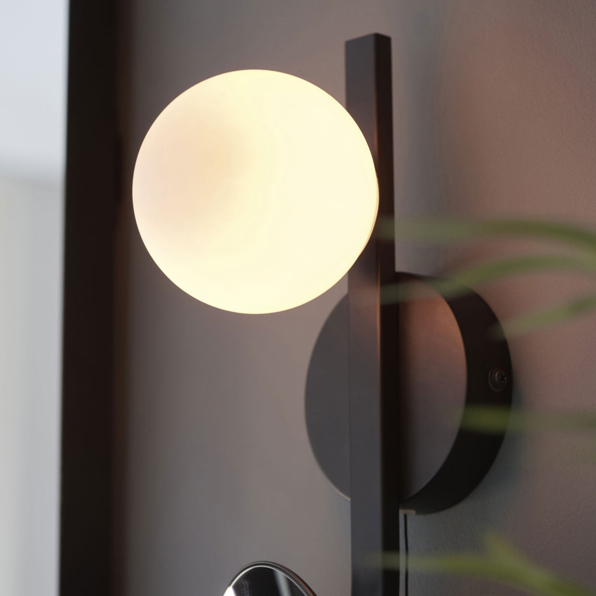 Close-up of the spherical glass shade of the modern black wall light.