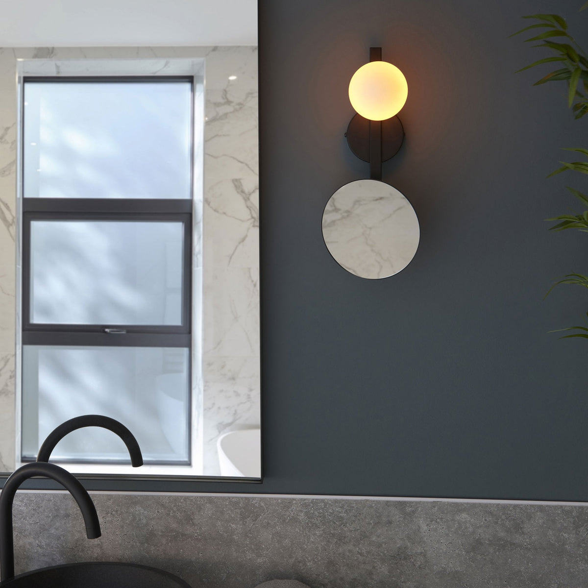 Modern wall light with a spherical bulb and a circular marble-effect disc in a bathroom setting.