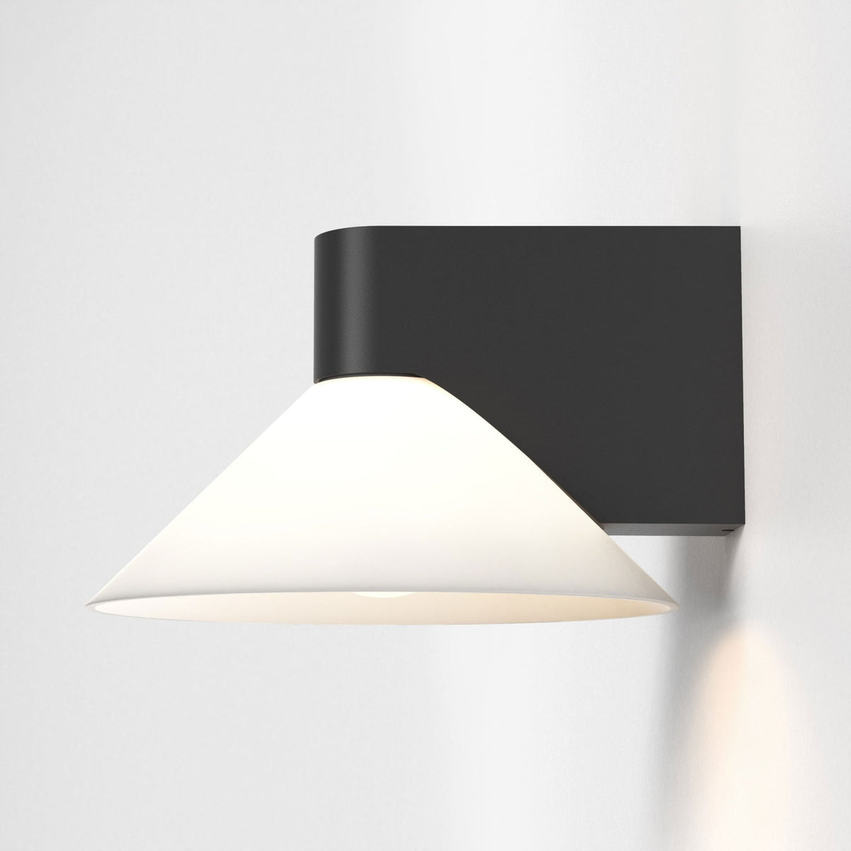 Black wall sconce with a white conical shade pointing downwards