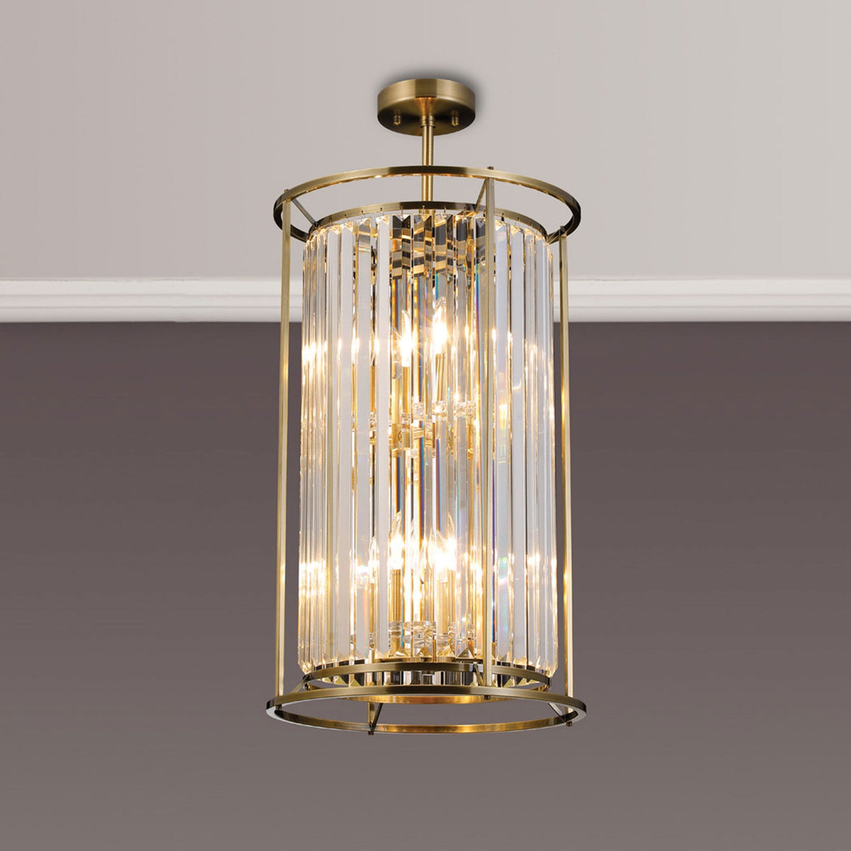 A cylindrical brass and crystal chandelier hangs from a white ceiling, casting a warm glow.