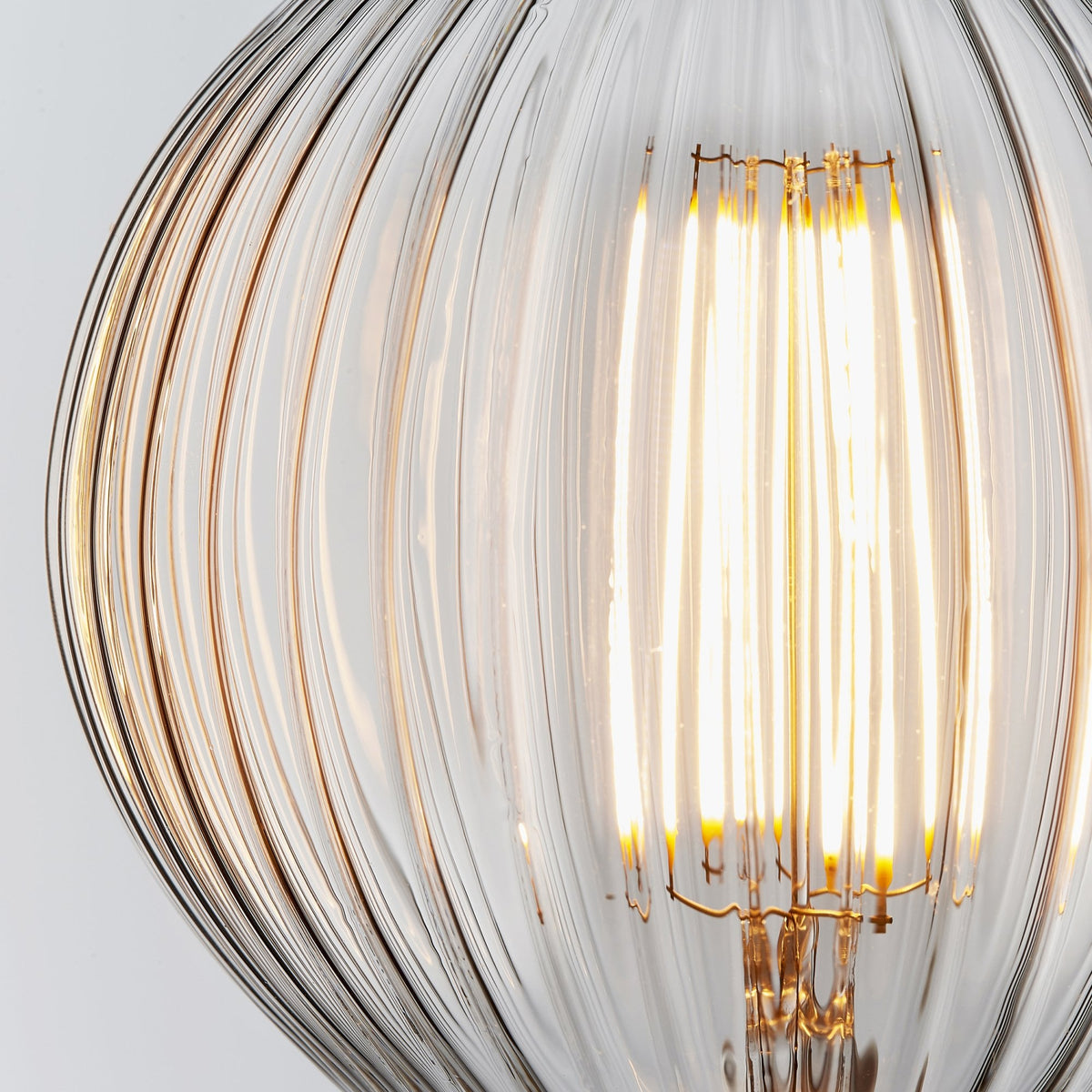 Close-up of a clear, ribbed glass LED light bulb with a warm glow.