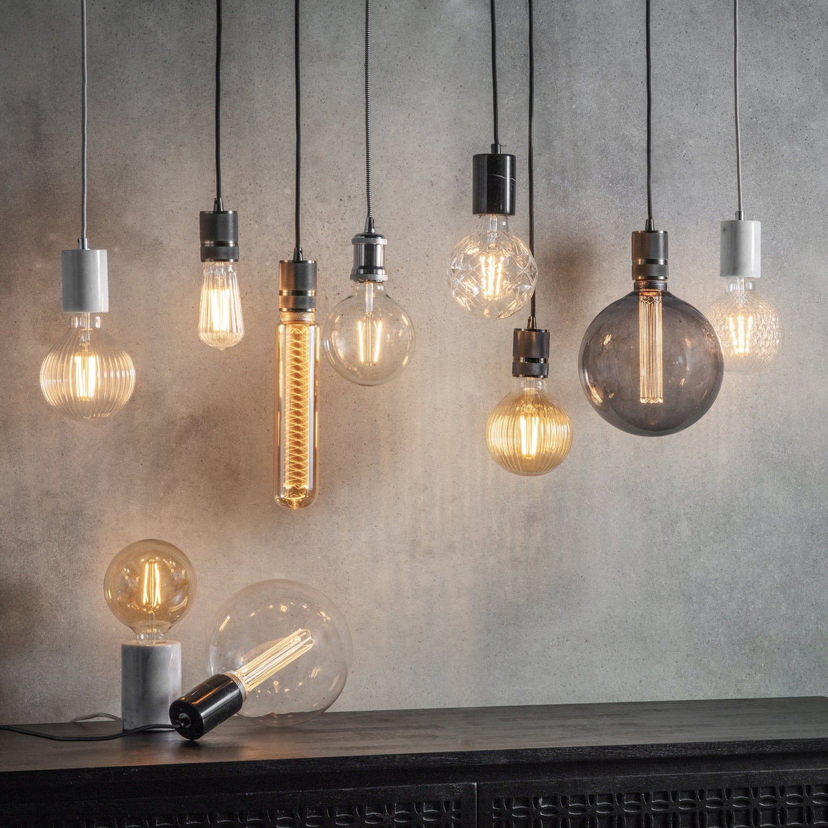Assortment of decorative LED light bulbs in various shapes and sizes, some hanging, some on a surface.
