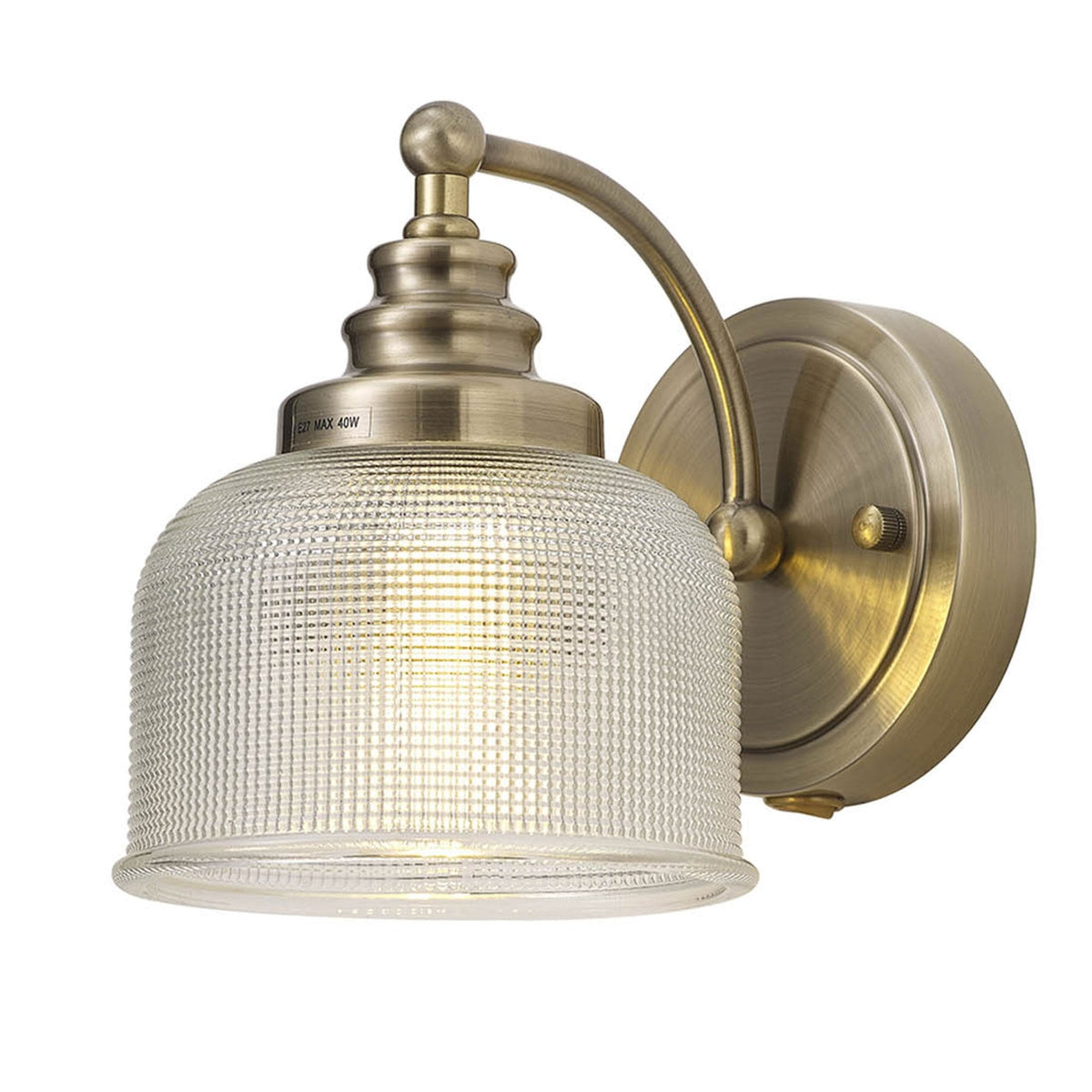 A brass wall light with a clear textured glass shade, unlit, against a white background.