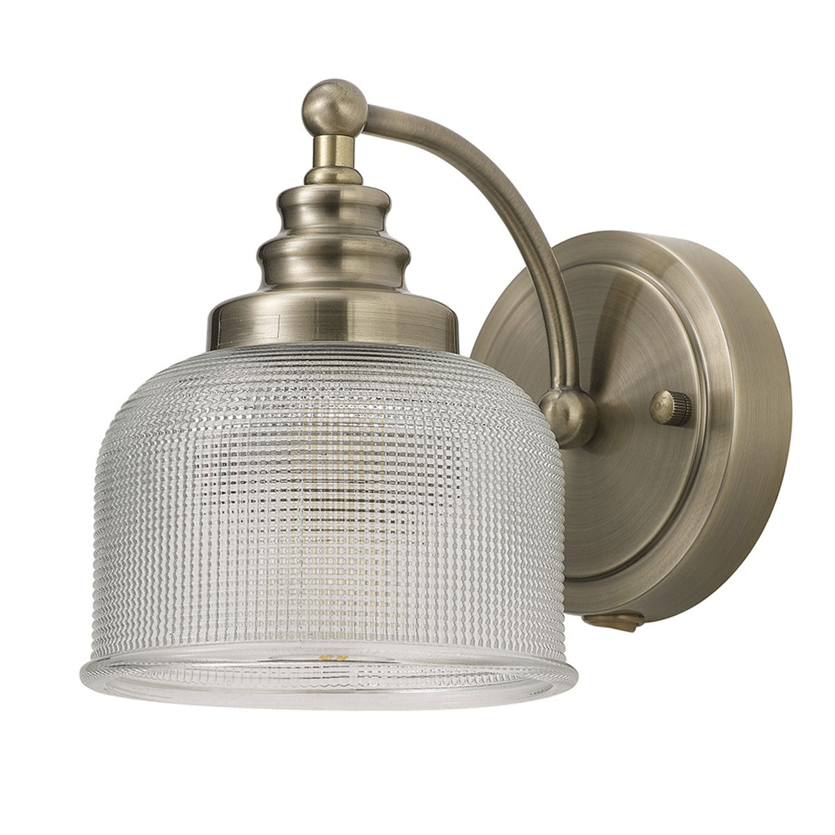 A brass wall light with a clear textured glass shade, unlit, presented against a white background.