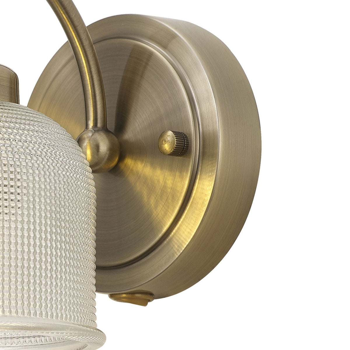 Close-up of the round brass base and curved arm of a wall light against a white background.