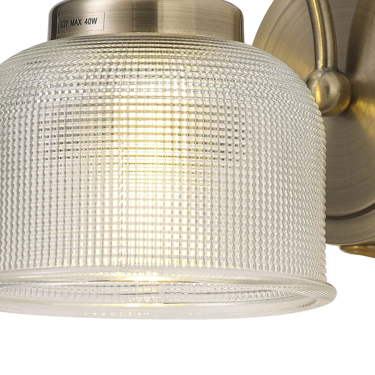 Close-up of the textured glass shade of a brass wall light, showing the light source.