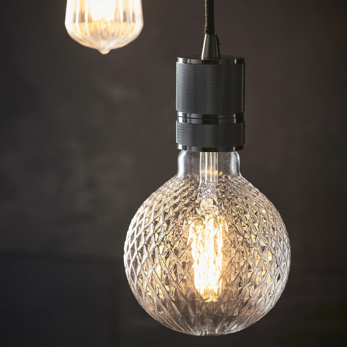 Close-up of a textured round bulb with visible filaments and a dark grey fixture.