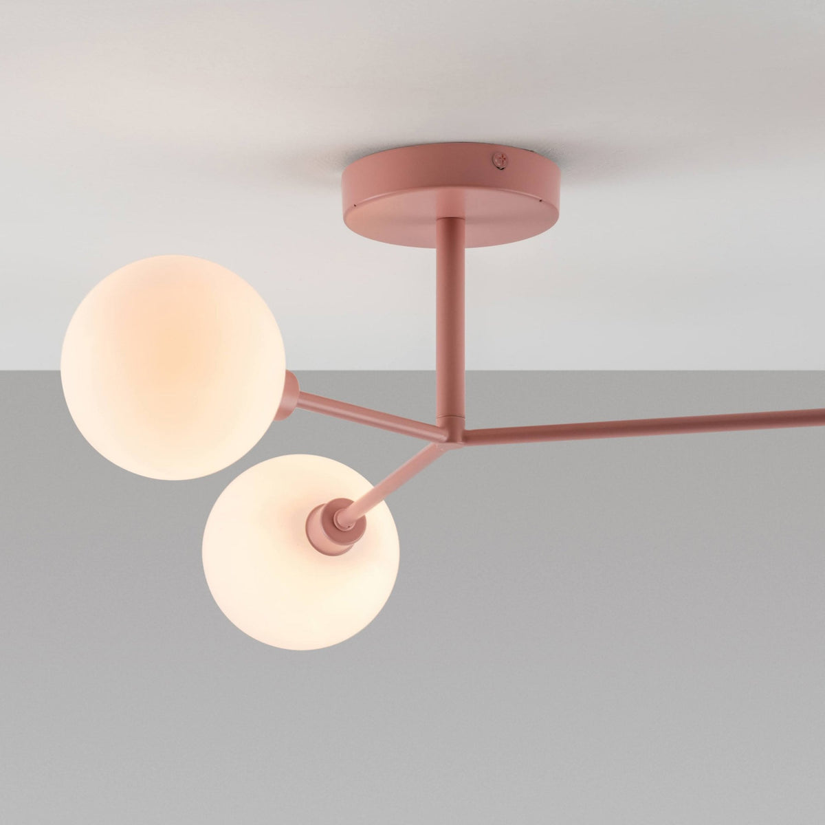 Pink ceiling light with three white globe shades