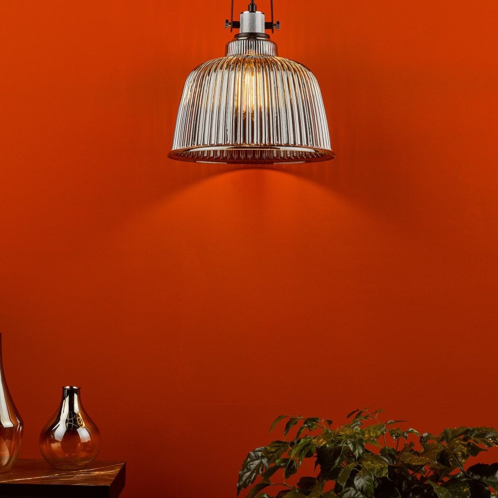 A ribbed glass pendant light hangs against a vibrant orange wall, casting a warm glow downwards.