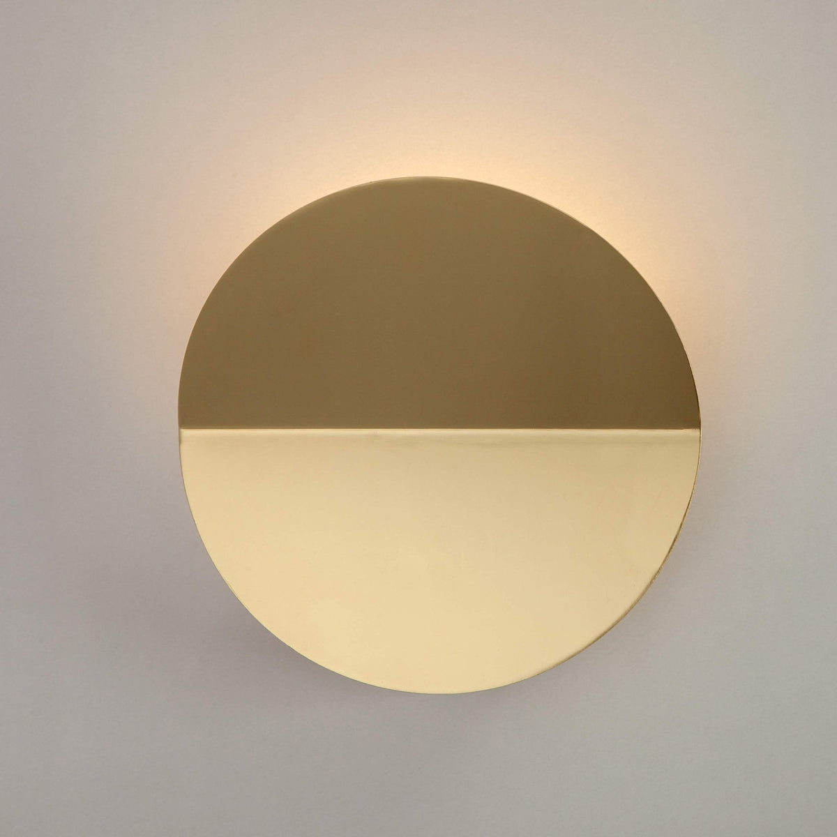 Round, bronze and brass wall light with a warm glow on the wall above.