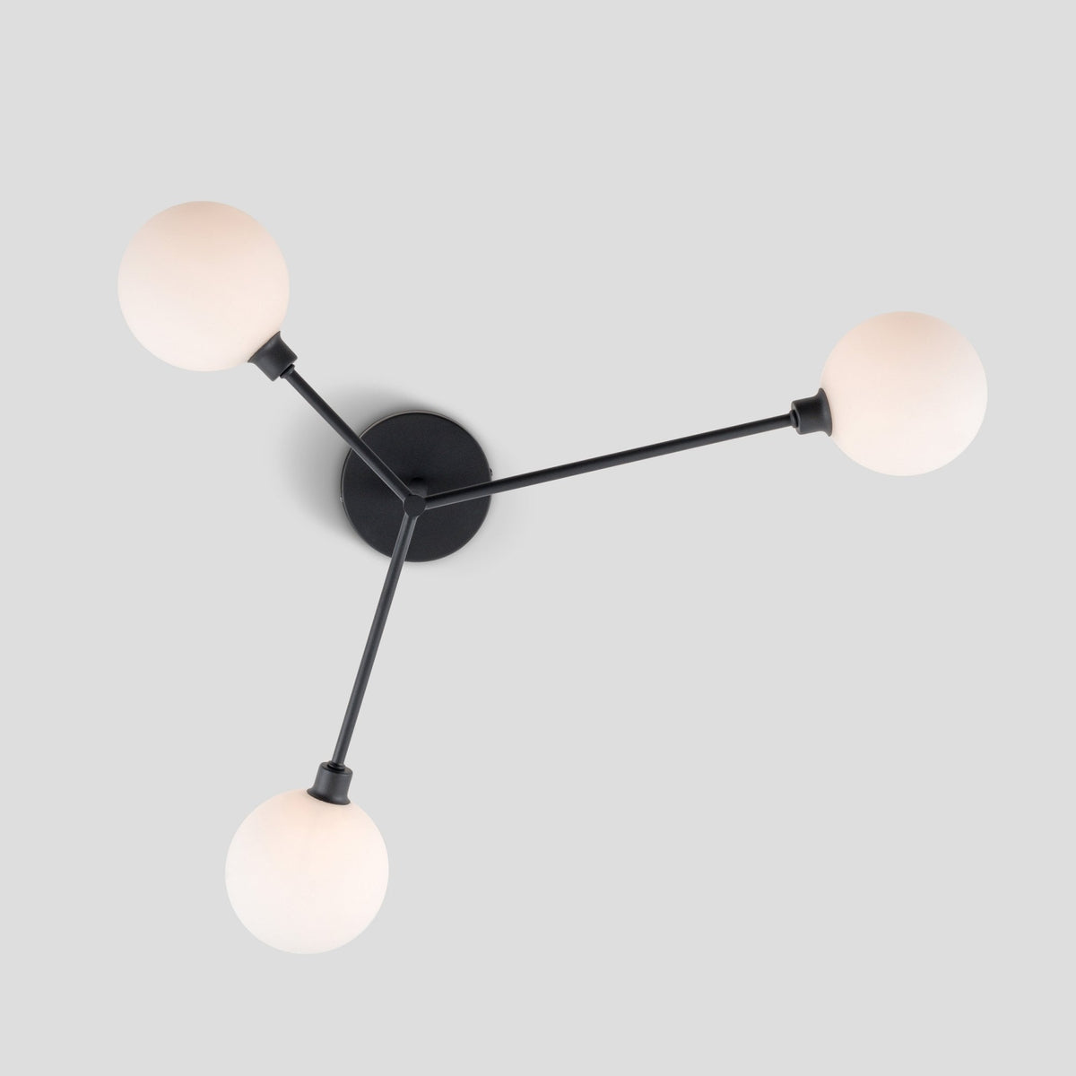 Black ceiling light with three arms extending to three white spherical bulbs