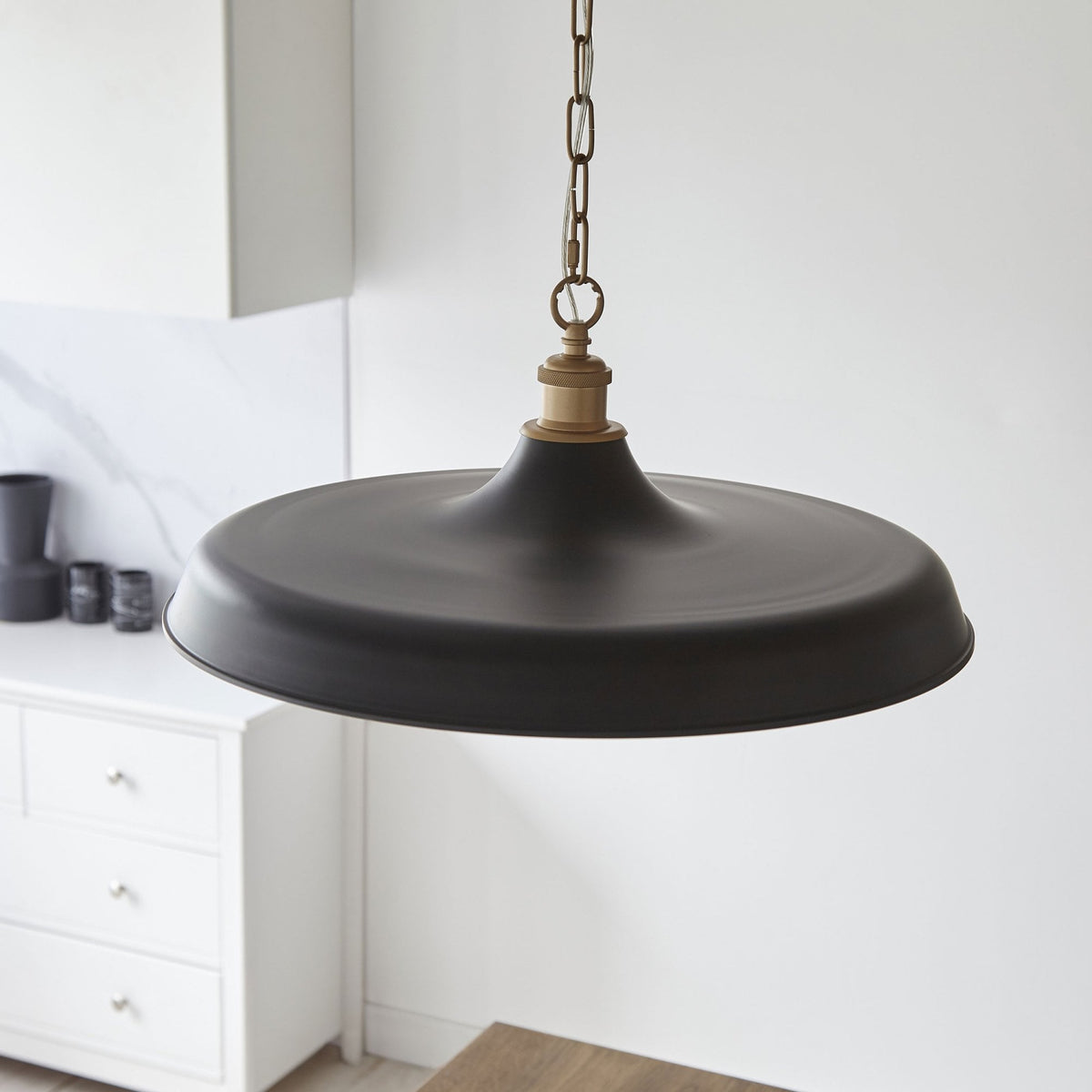 Un luminaire suspendu noir et or de style moderne, idéal pour un éclairage ciblé au-dessus d'une surface.