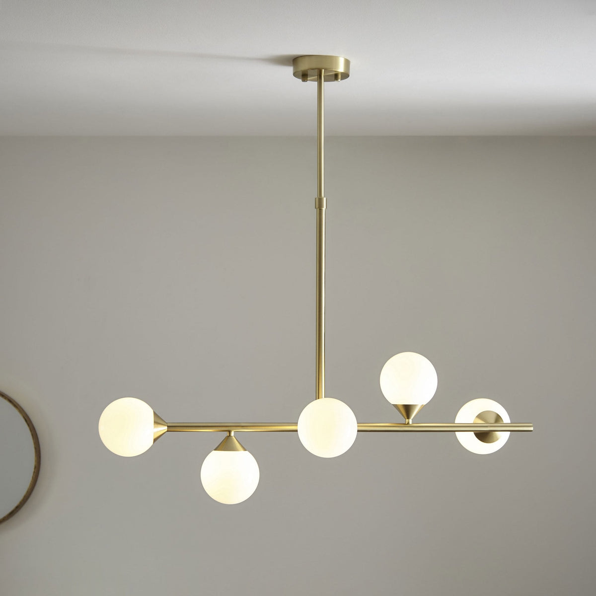 A modern brass chandelier with five globe lights, perfectly suited for contemporary interiors and elegant dining spaces.