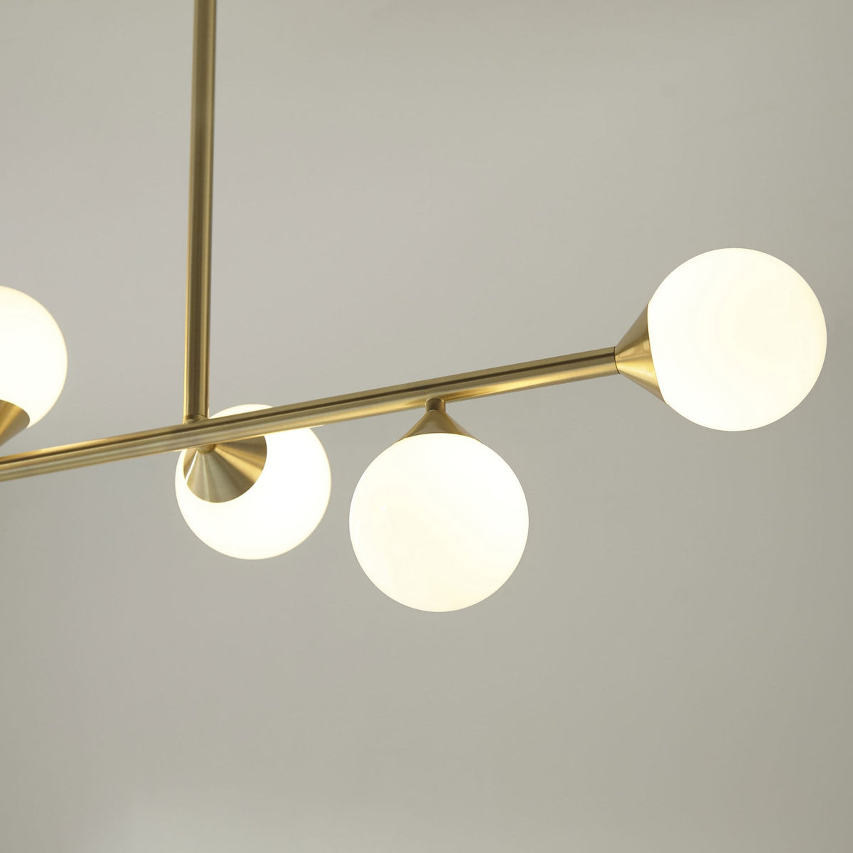 A close-up of a brass chandelier's illuminated globe lights, showcasing its contemporary and clean design.