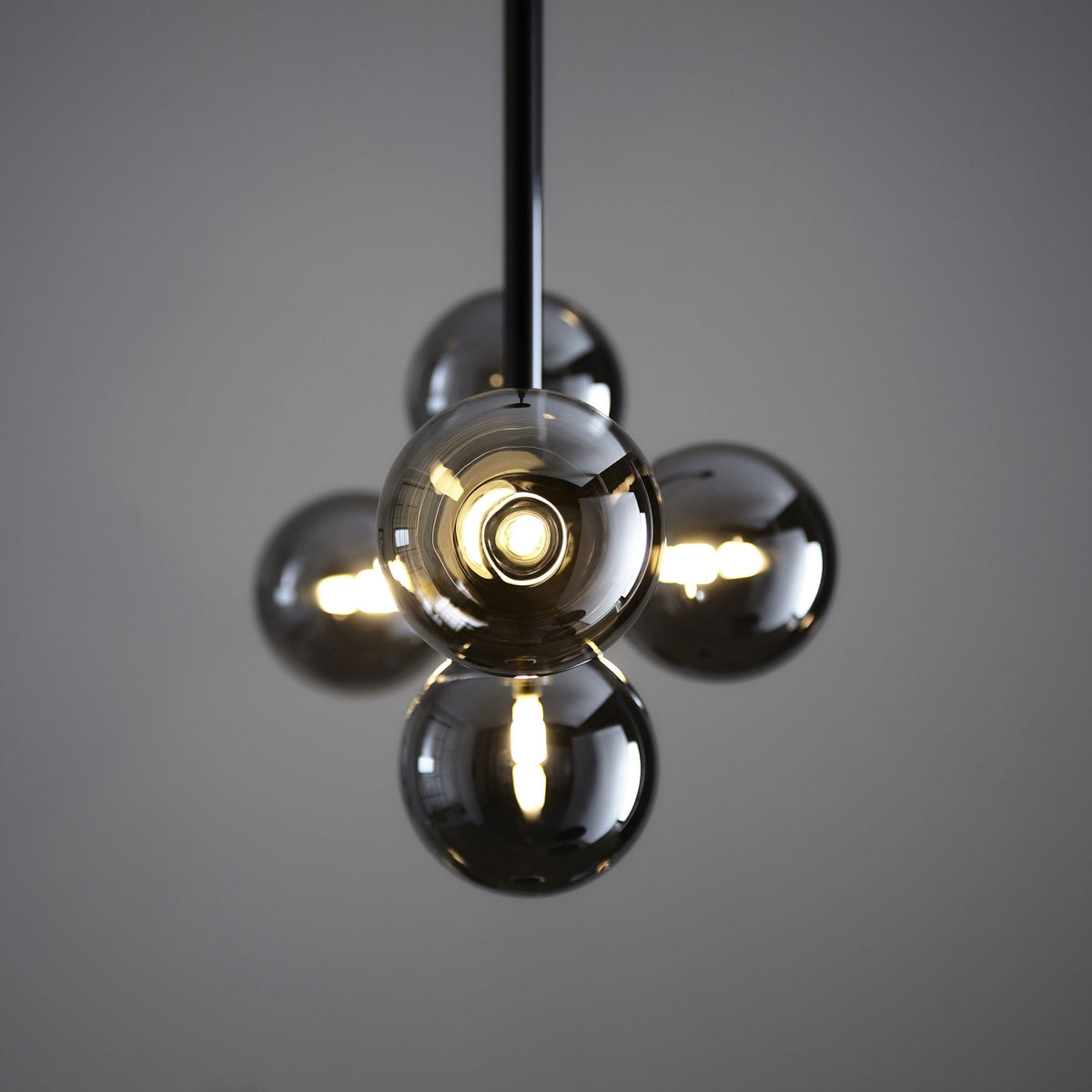 A close-up of a modern chandelier featuring smoky glass globes with illuminated filaments inside.
