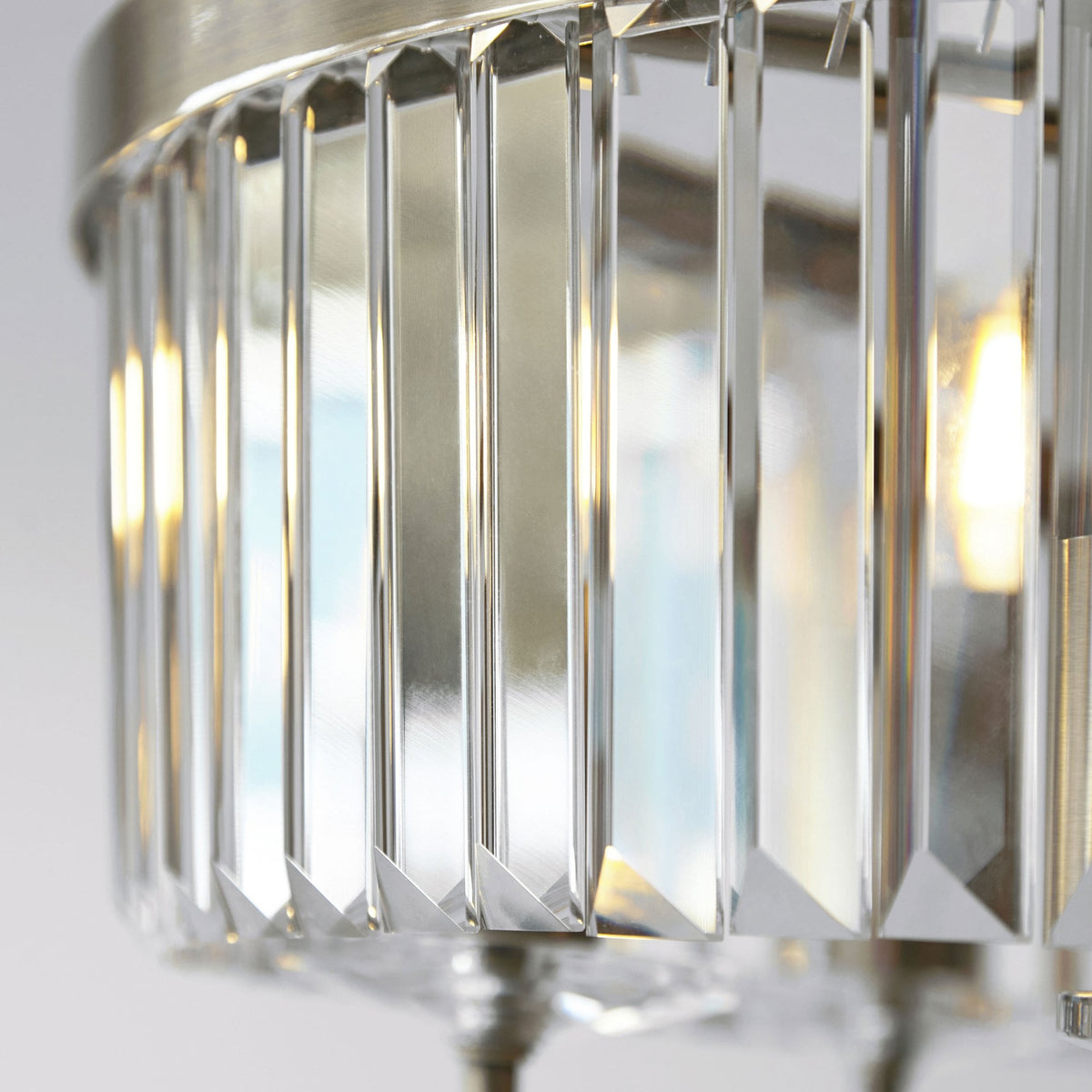 A close-up of the elegant crystal rods and brass details on the Tiffany round semi-flush ceiling light.
