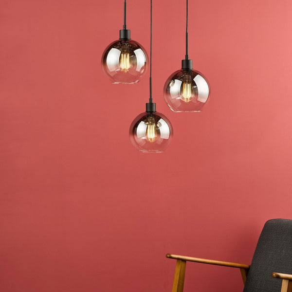 Three pendant lights with smoked glass shades and exposed filament bulbs hang against a red wall.