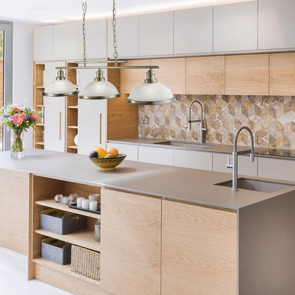 Two pendant lights illuminating a modern kitchen island with wooden cabinets and a grey counter.