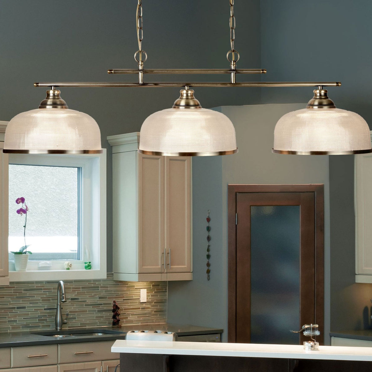Three pendant lights illuminating a kitchen island and providing a warm glow.