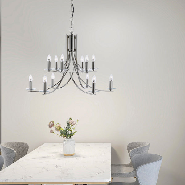A modern 12-light chandelier above a dining table with chairs and a flower arrangement.