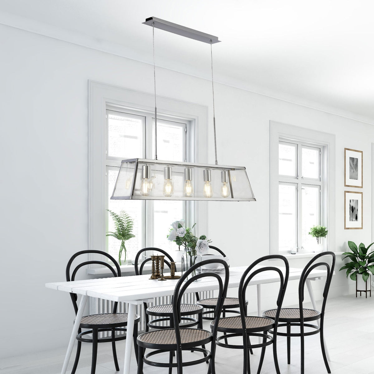 A dining room featuring a modern chrome rectangular pendant light above a white dining table.