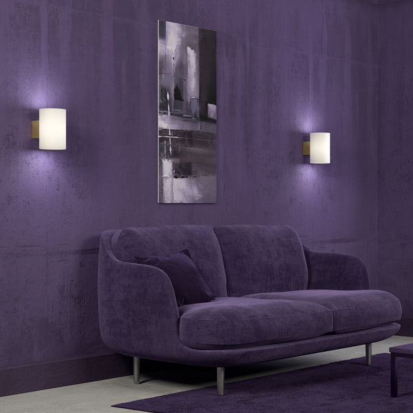 A cosy living room with purple walls, two wall lights, and a purple sofa.