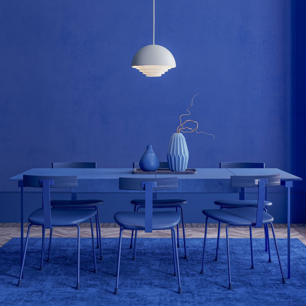 A dining room with an all-blue aesthetic, featuring a table, chairs, and decorative items.