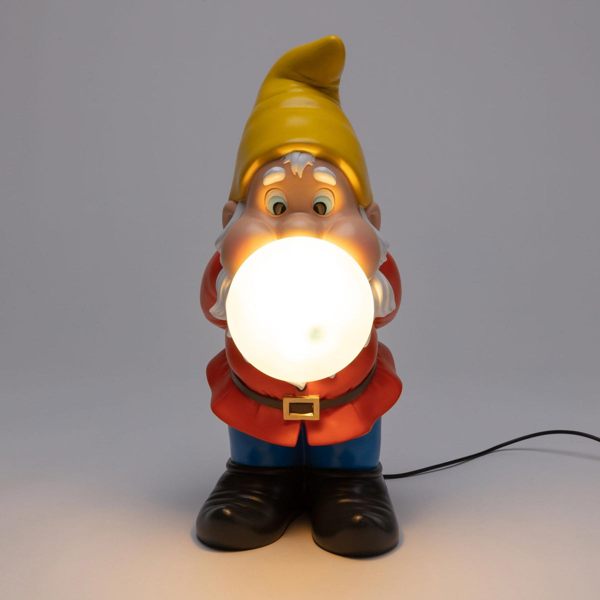 Gnome lamp with a yellow hat, red shirt, blue pants, and black shoes, holding a glowing white orb
