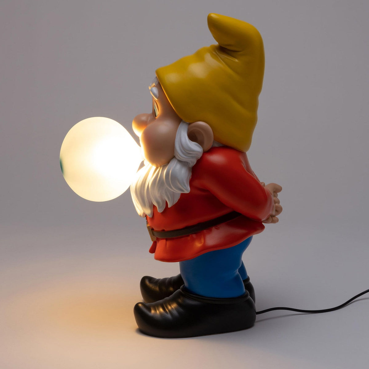 Seletti Gummy Dimmable Table Lamp Snooping Edition, a gnome in a red jacket and yellow hat holding a light