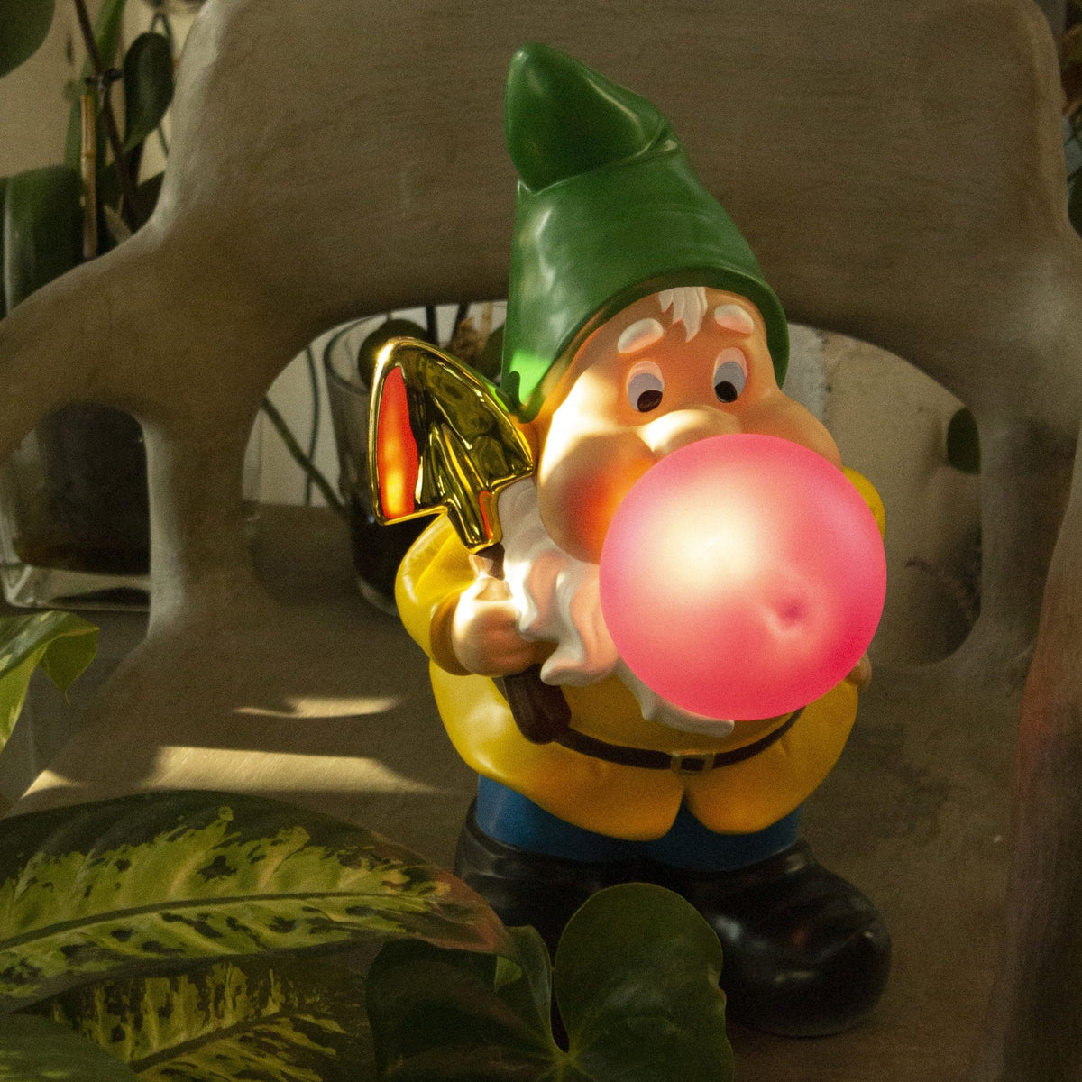 A garden gnome holding a shovel, blowing a glowing pink bubble gum bubble.