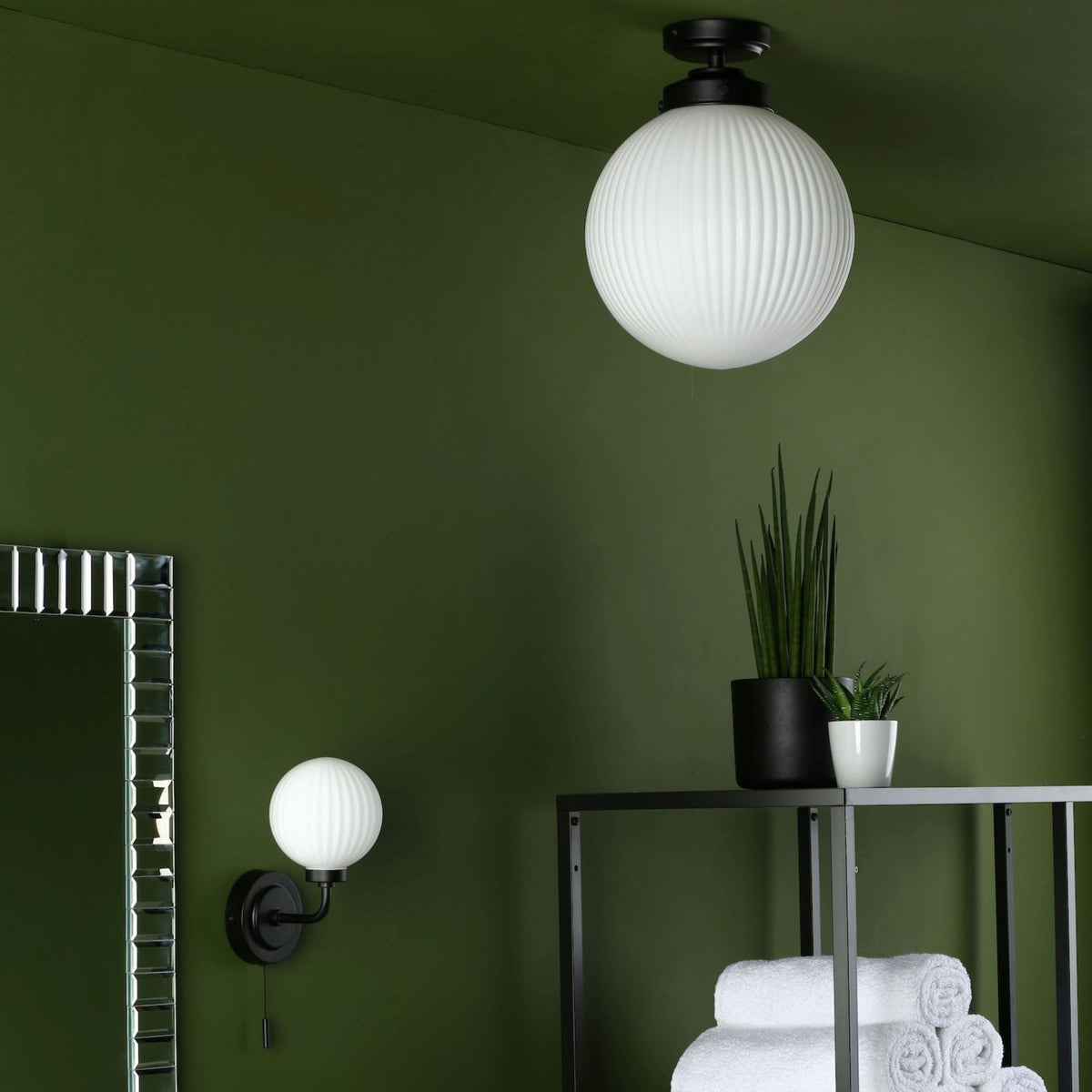 Green room with a white globe ceiling light, a white globe wall light, and a mirror.