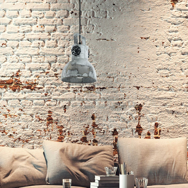 An industrial-style pendant light hangs above a sofa in a room with a distressed brick wall.