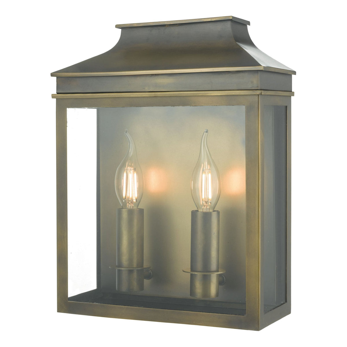 Antique brass outdoor wall lantern with two lit candle-style bulbs, clear glass panels, and a peaked roof.