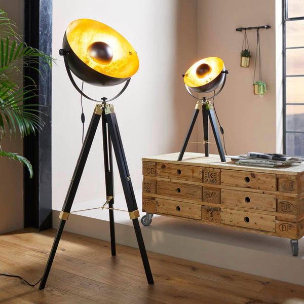 Two black and gold industrial tripod lamps illuminate a contemporary living space.