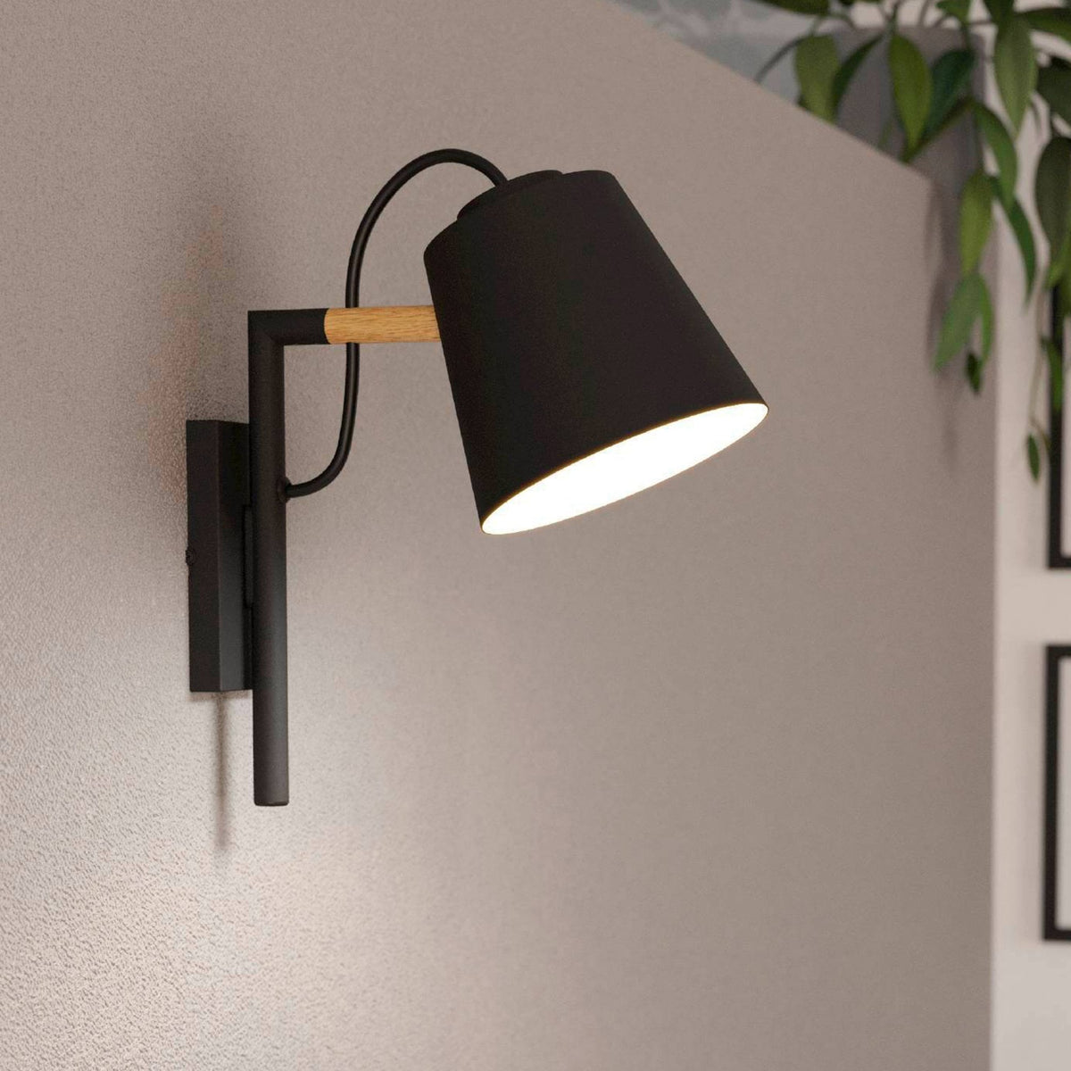 Black and wood wall lamp with light on, illuminating a grey wall.