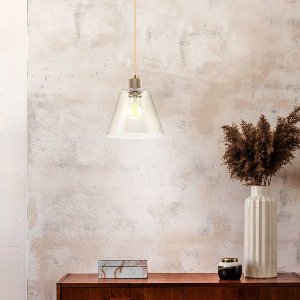 A glass pendant light illuminating a rustic wall above a wooden cabinet with decor.