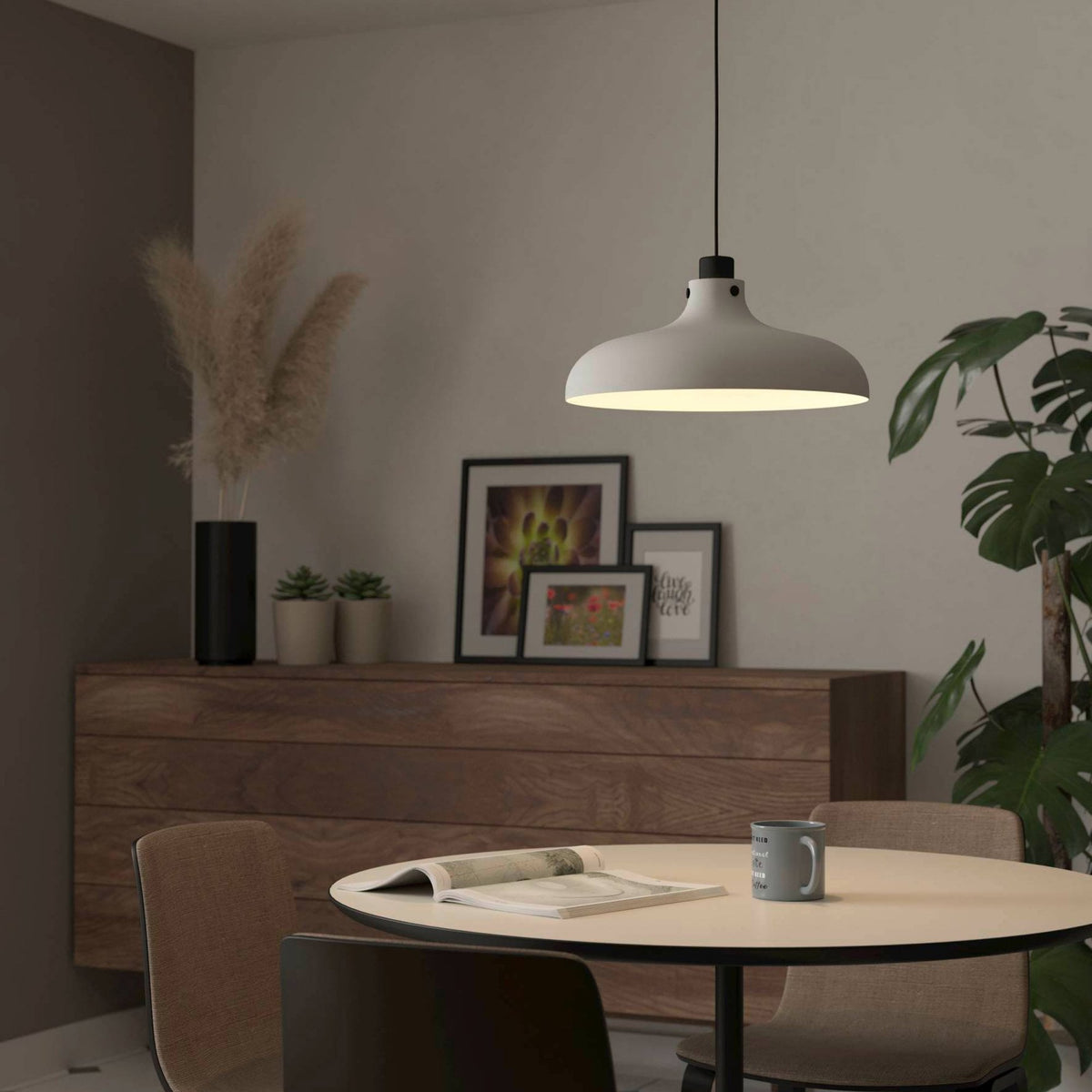 A white pendant light hangs over a dining table, illuminating the setting.