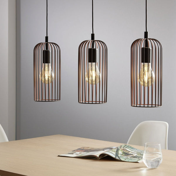 Three pendant lights with black cages illuminate a modern dining table.
