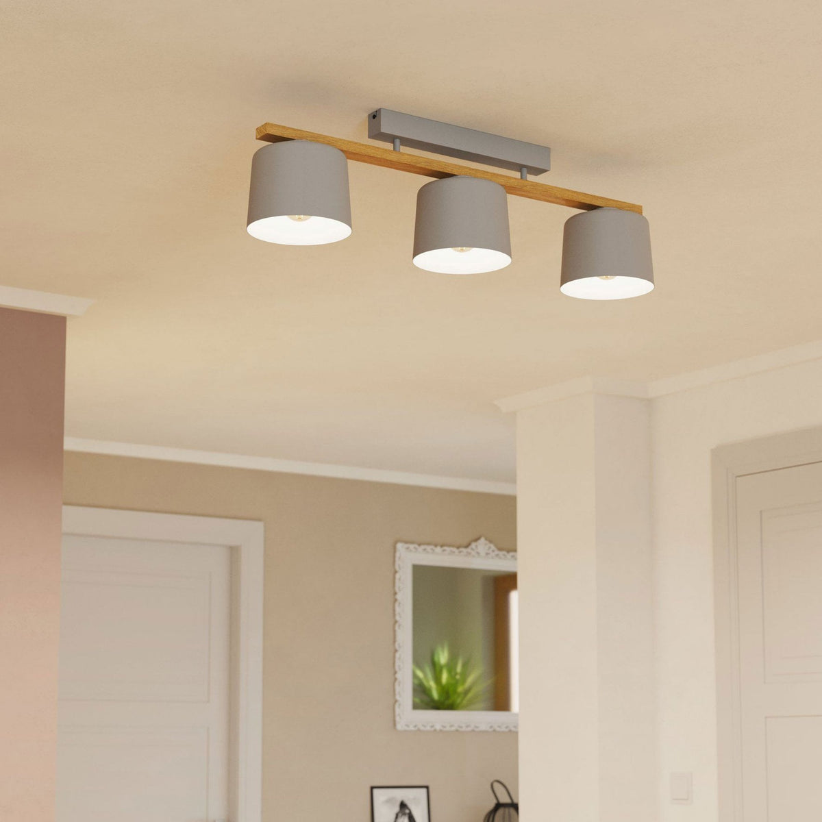 A three-bulb ceiling light with light grey shades and a wooden beam, illuminating a hallway.