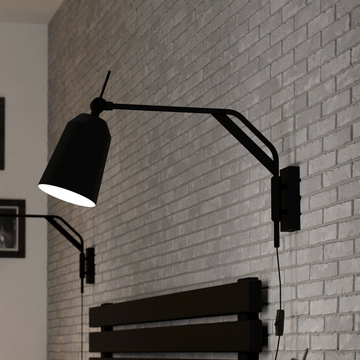 A black wall lamp with an adjustable arm and conical shade illuminates a grey brick wall.