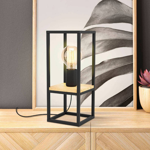 A black framed table lamp with a light wood base on a wooden surface.
