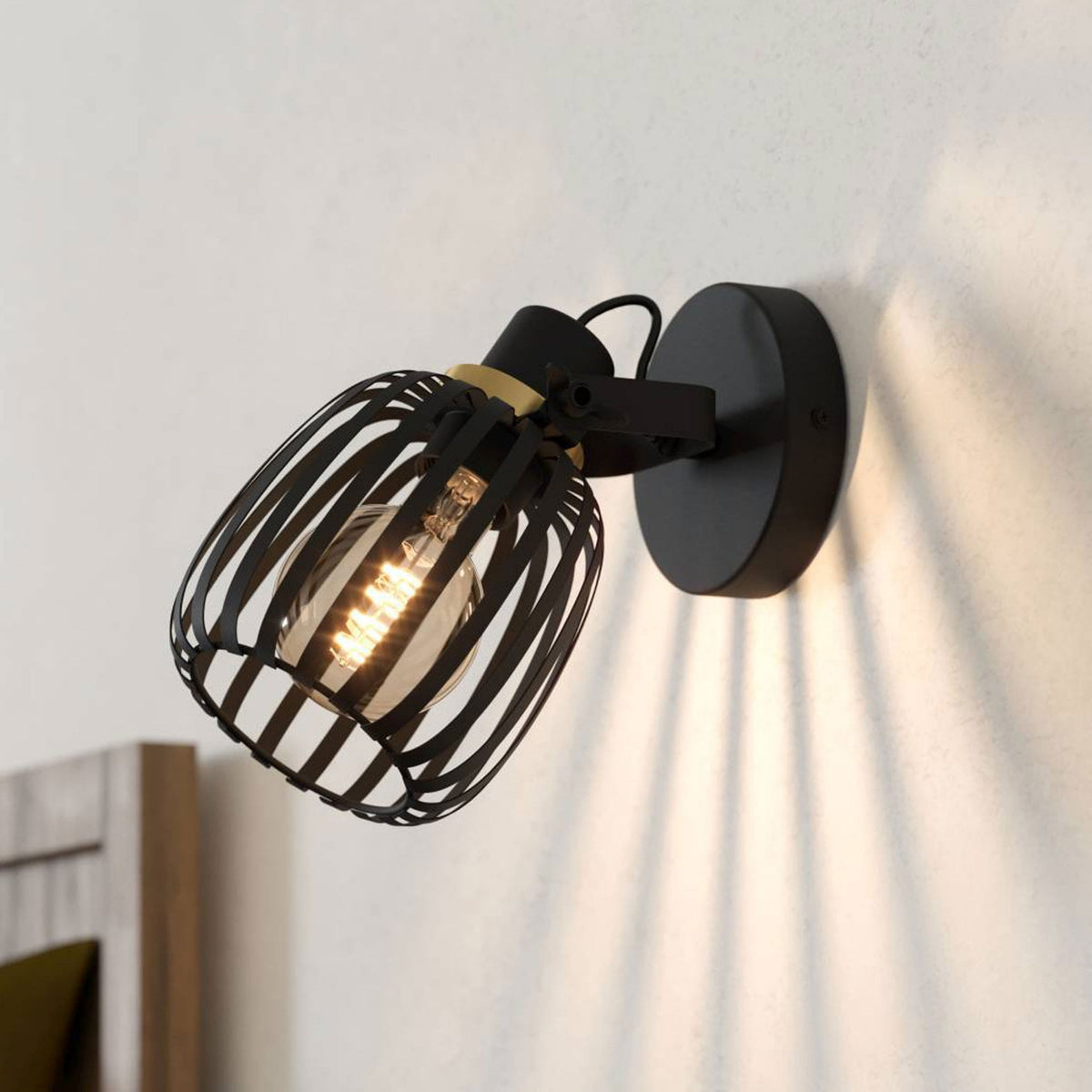A black industrial-style wall light illuminates a bedroom setting.