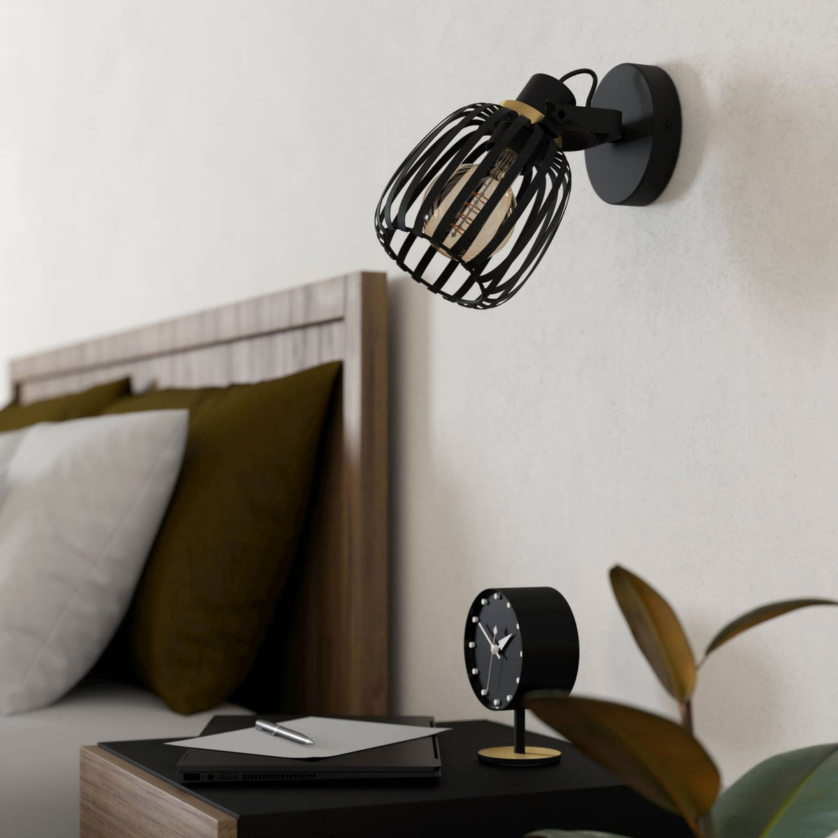 A black industrial wall light illuminates a bedside table with an alarm clock.