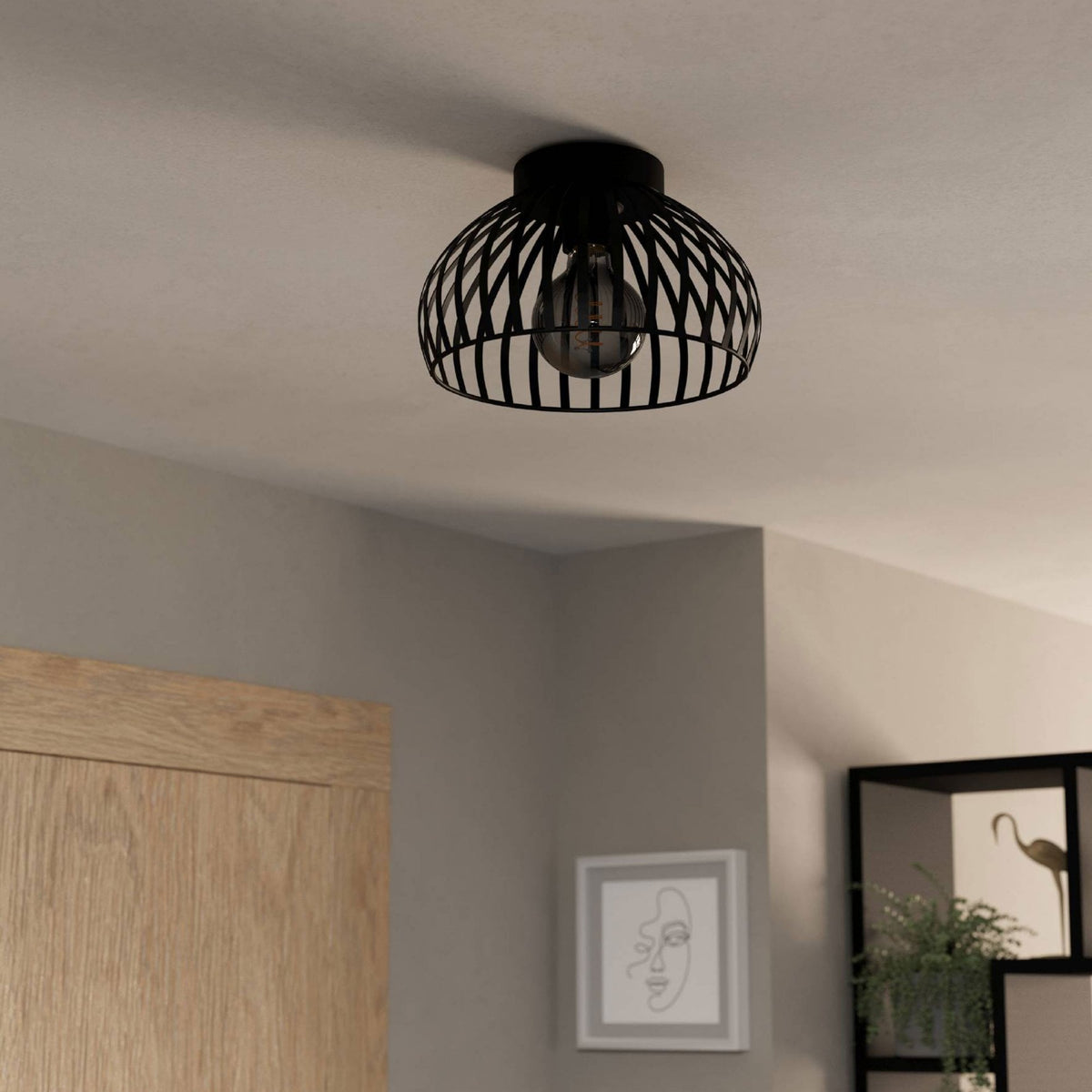 A black cage ceiling light illuminating a room with a decorative shadow pattern.