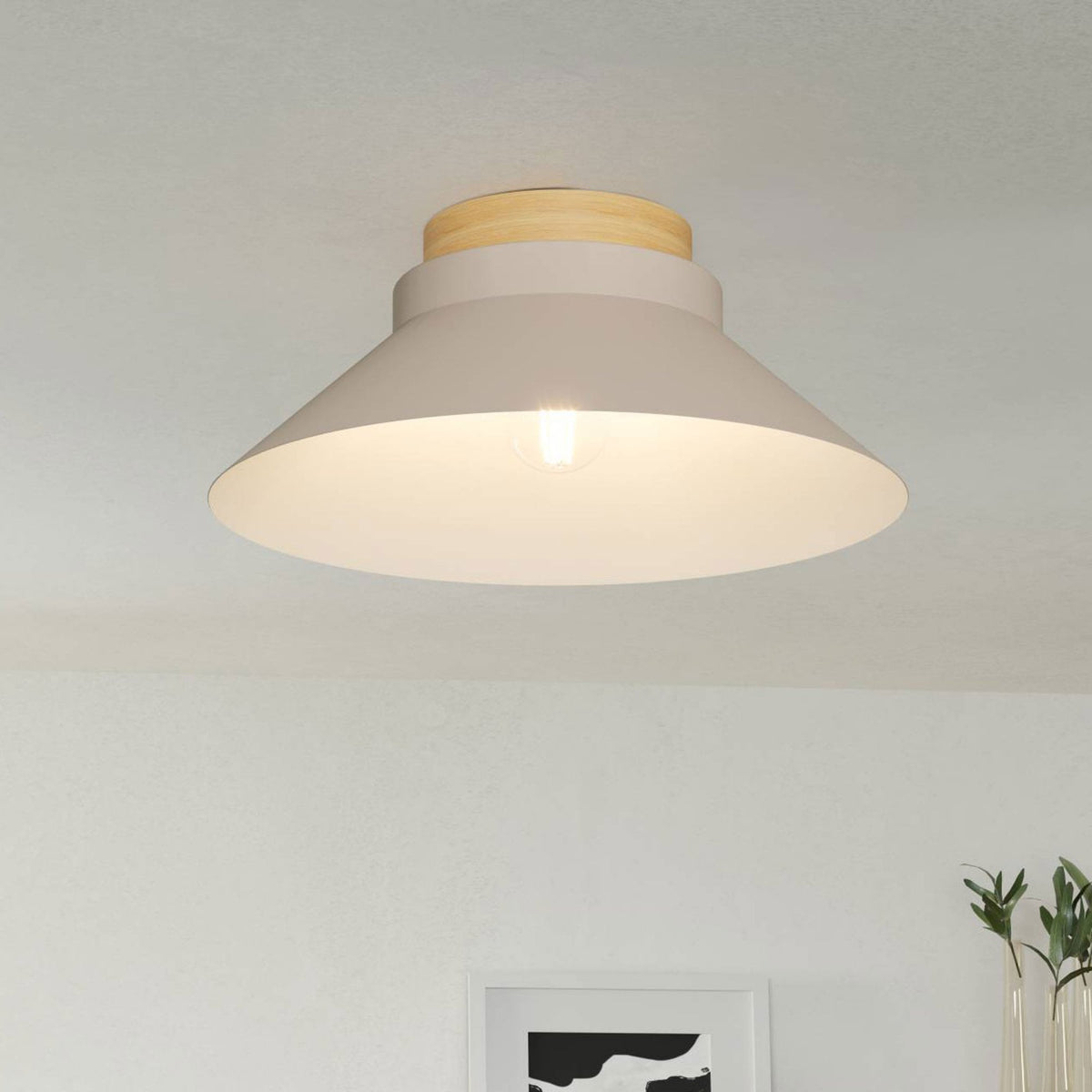 A modern beige flush mount light with a wooden top and exposed bulb on a white ceiling.
