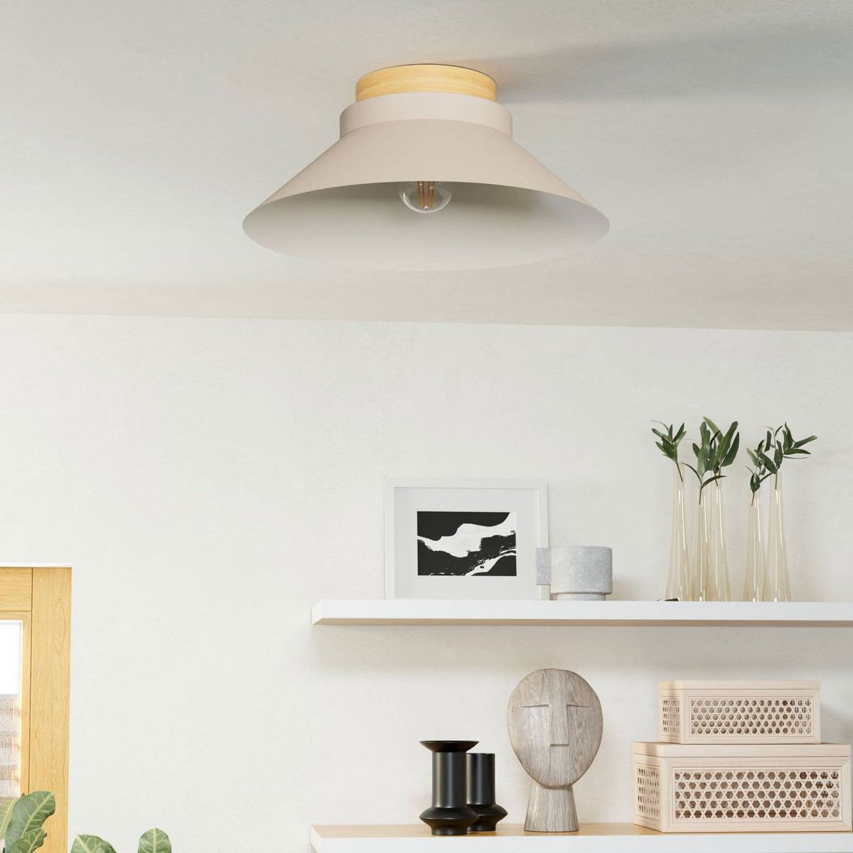 A beige flush mount light with a wooden top on a white ceiling above a shelf.
