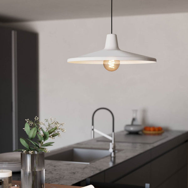 White ceiling lamp with exposed bulb hangs above a kitchen island with a sink and tap.