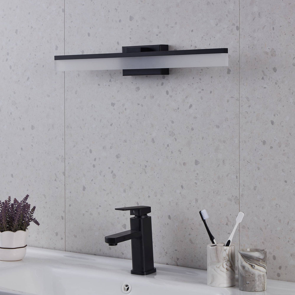 A black rectangular LED bathroom mirror light, unlit, above a sink with a black tap.